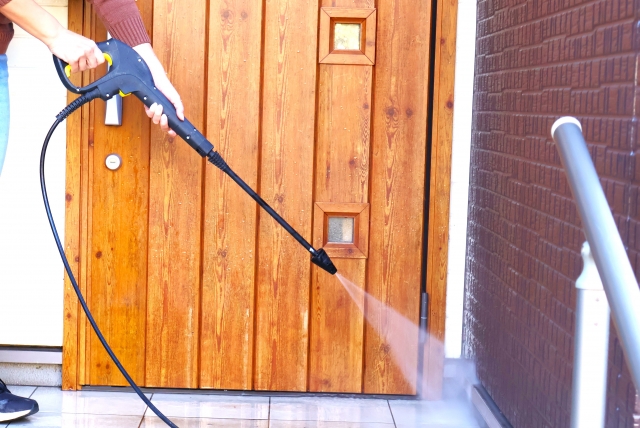 玄関を高圧洗浄する人